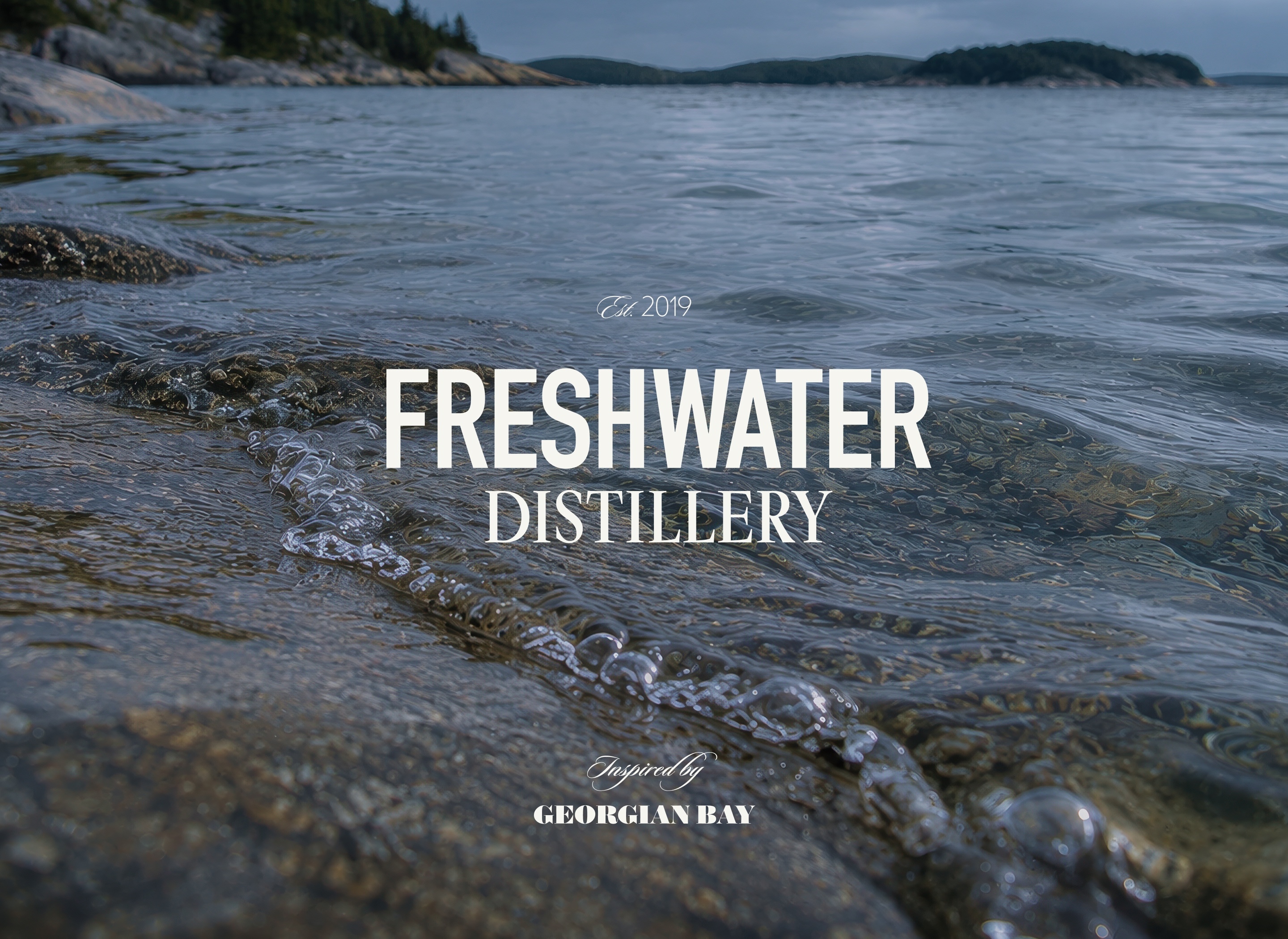 Freshwater Distillery wordmark over a photograph of Georgian Bay shoreline and clear freshwater.